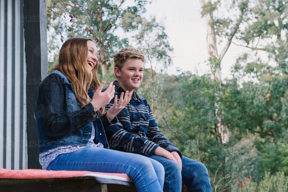 young teens sitting in a cubby house in the woods - Australian Stock Image