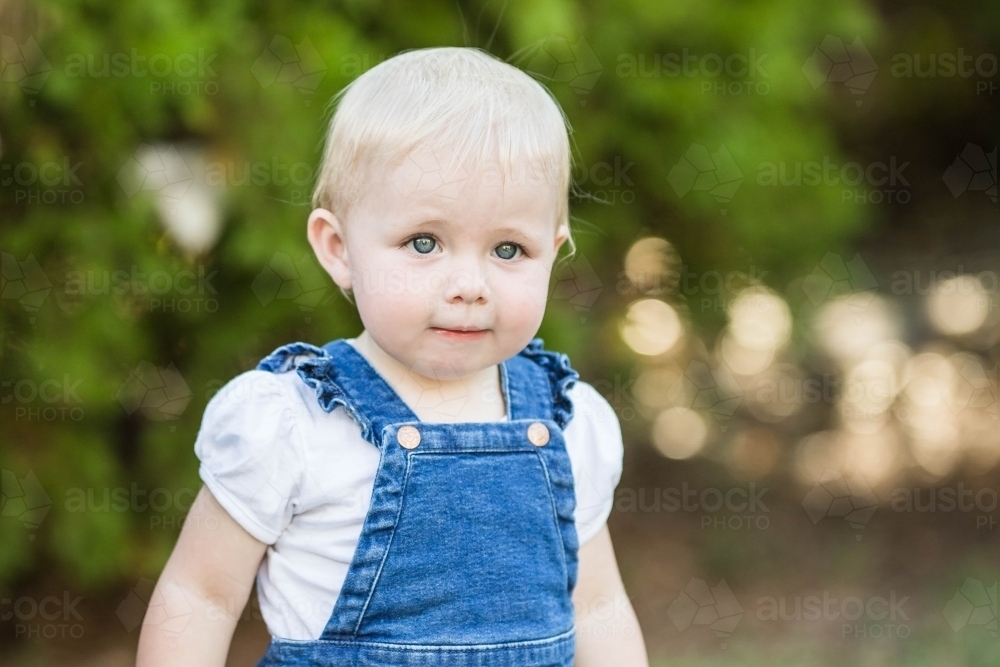 Young toddler girl with blonde hair outside in garden - Australian Stock Image