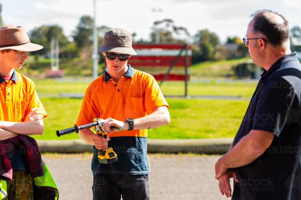 young trade apprentices at tool demonstration trying out drill - Australian Stock Image