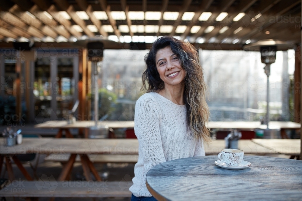Young Turkish woman drinking coffee at cafe - Australian Stock Image