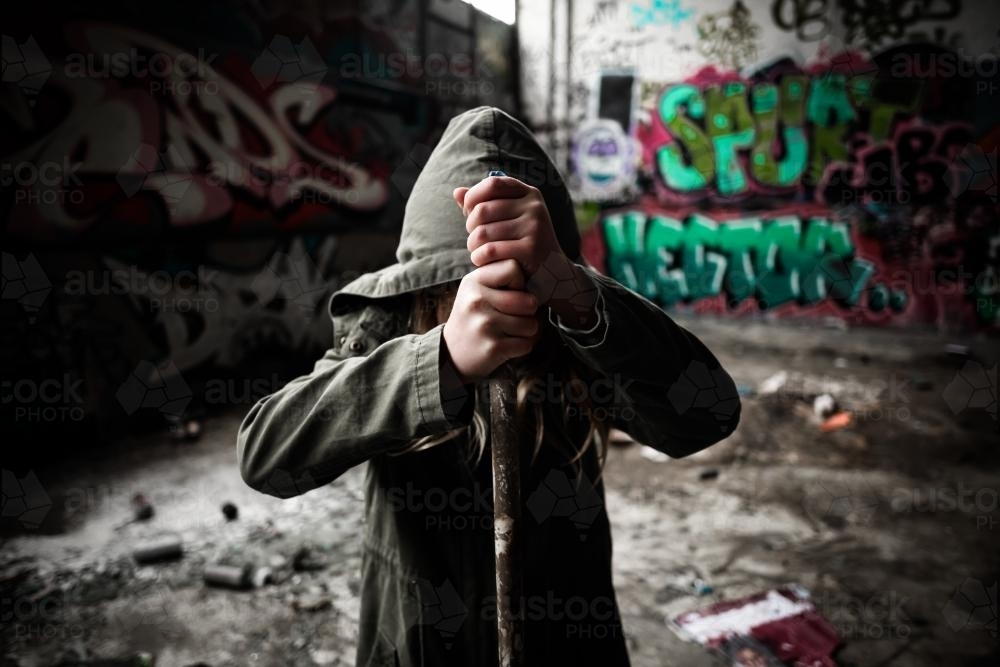 Young vandal holding a pipe in a pose of strength and defiance - Australian Stock Image