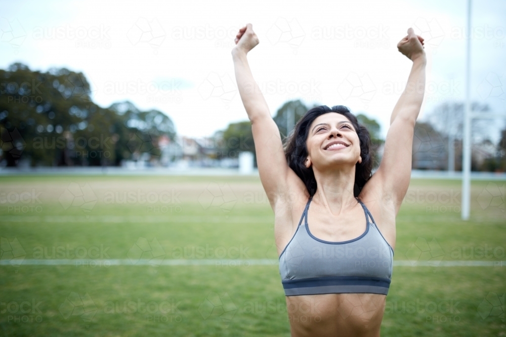 Young woman achieving fitness goals on sports field - Australian Stock Image