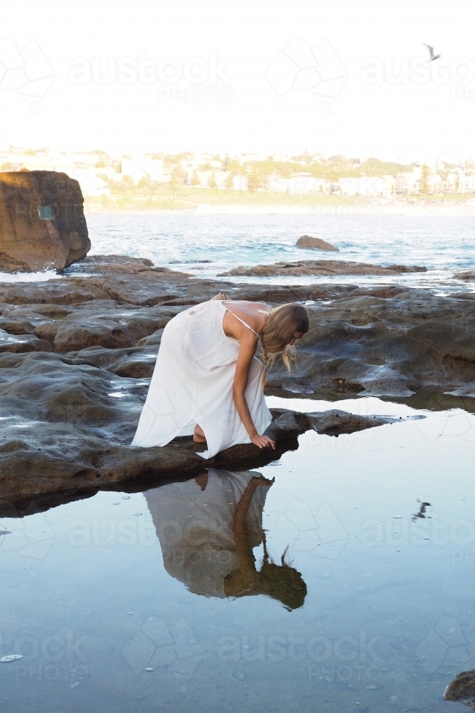 Young woman beside calm coastal rock pool - Australian Stock Image