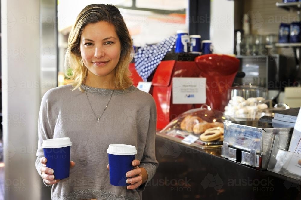 young woman buying takeaway coffees at a cafe - Australian Stock Image