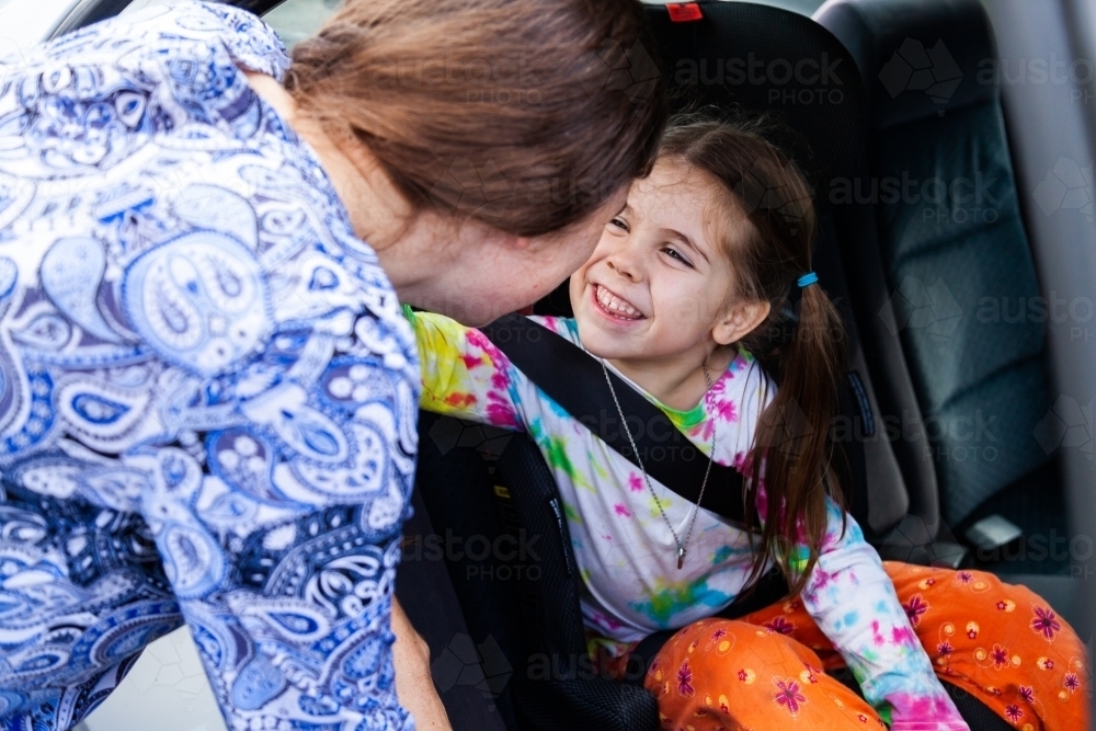 Young woman clicking child into car booster seat - Australian Stock Image