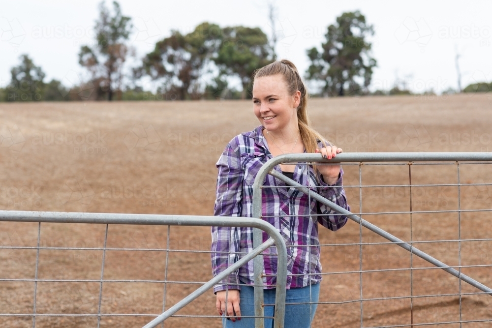 Young woman closing a gate on a rural property - Australian Stock Image