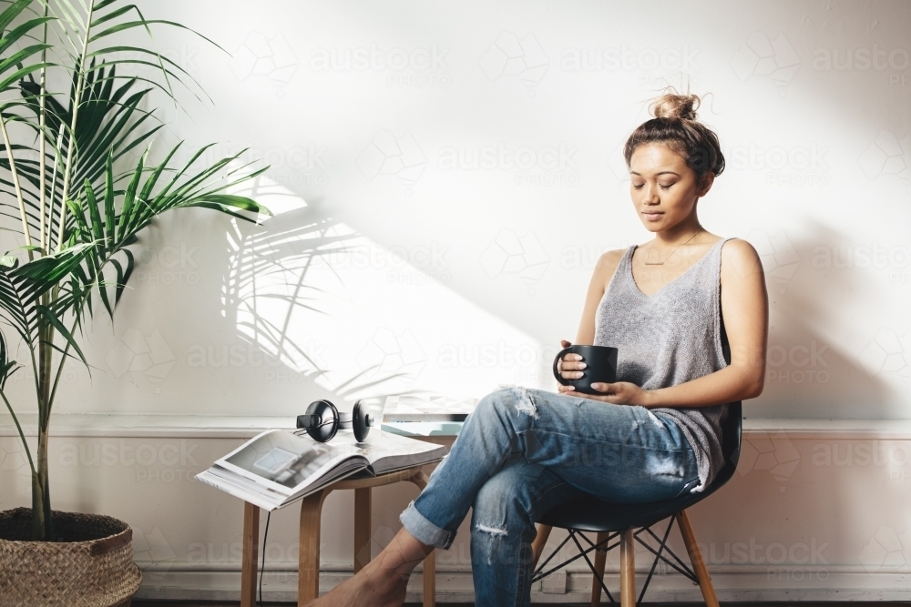 Young woman deep in thought holding a coffee with closed eyes - Australian Stock Image