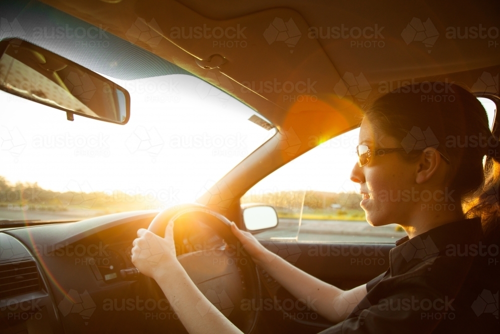 Young woman driving her car with lens flare - Australian Stock Image