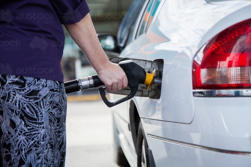 Young woman filling her car up with petrol at the service station - Australian Stock Image