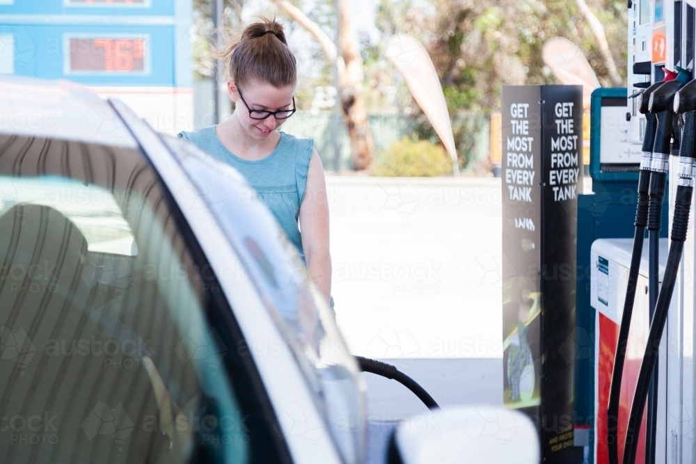 Young woman filling up car at petrol pump - Australian Stock Image
