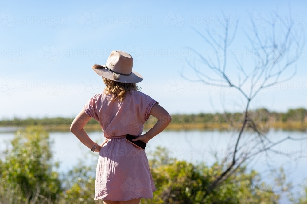 young woman from behind looking out over river - Australian Stock Image