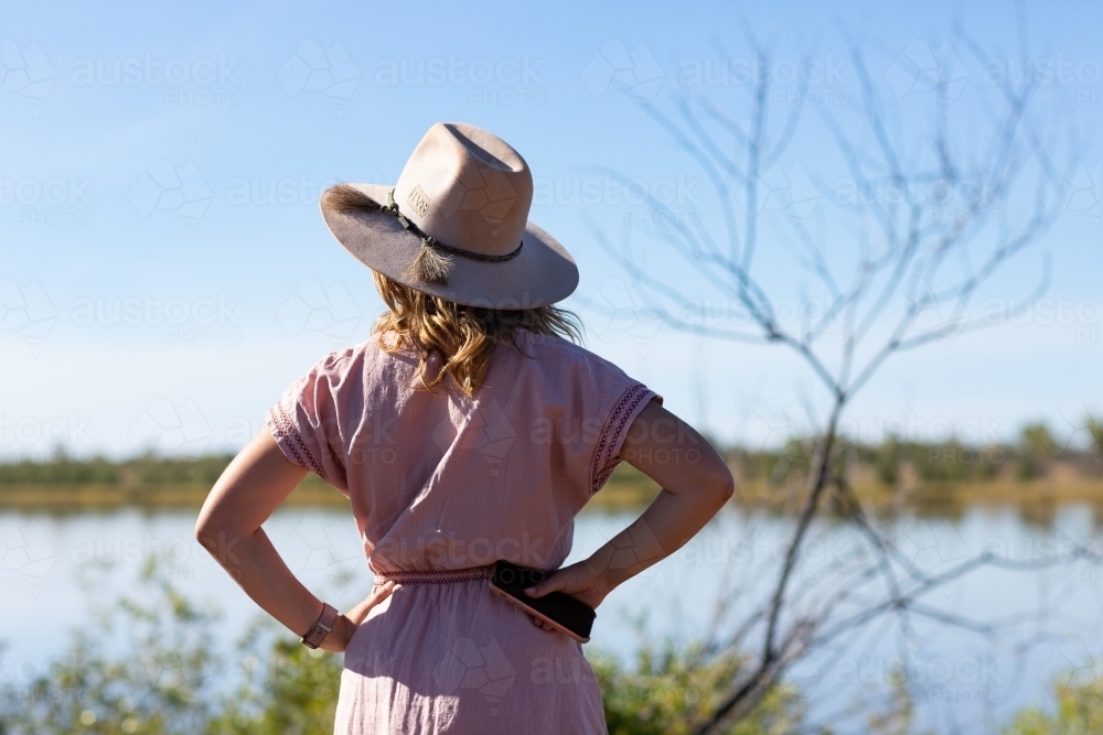 young woman from behind looking out over river - Australian Stock Image