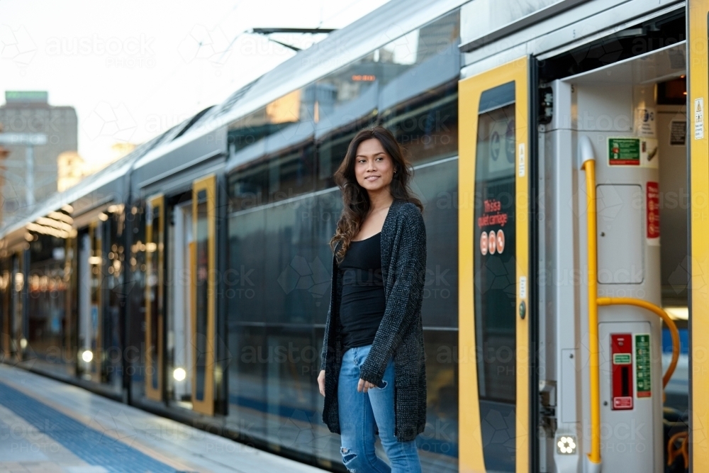 Young woman getting off train at train station - Australian Stock Image