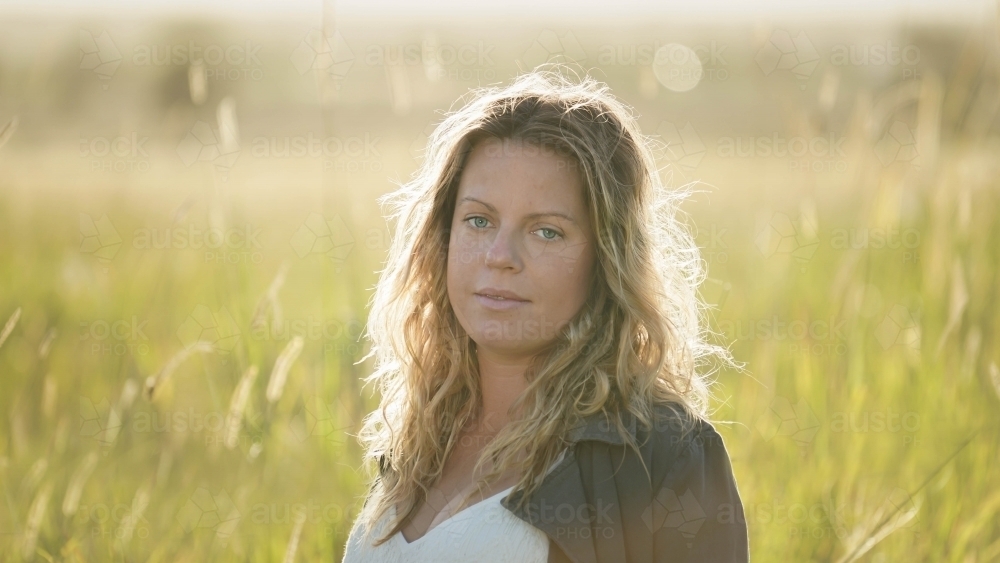 Young woman headshot with sunflare behind - Australian Stock Image