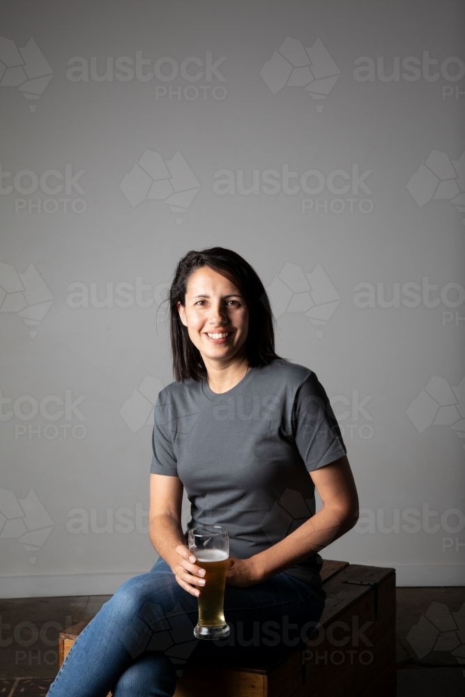 Young woman holding a glass of beer, relaxed and happy - Australian Stock Image