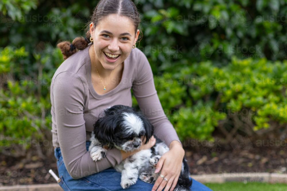 young woman holding a pet dog and making eye contact with the viewer - Australian Stock Image