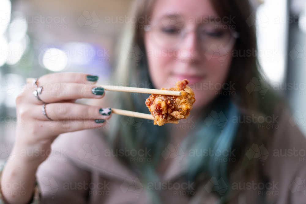 young woman holding kara age with chopsticks - Australian Stock Image