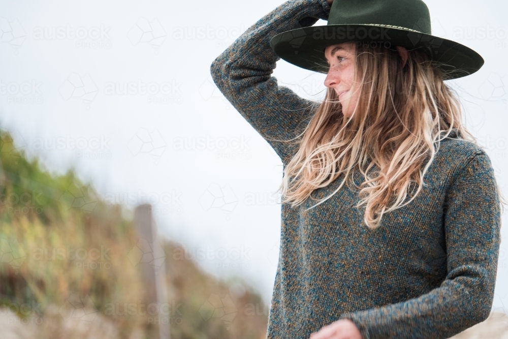 Young woman holding onto her hat. - Australian Stock Image