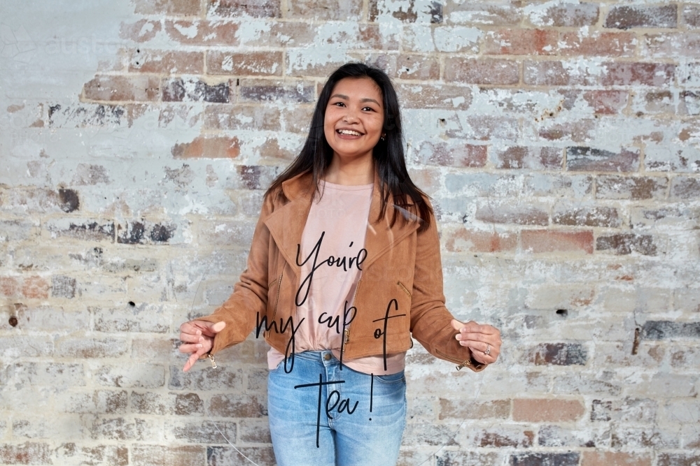 Young woman holding transparent sign in front of brick wall - Australian Stock Image