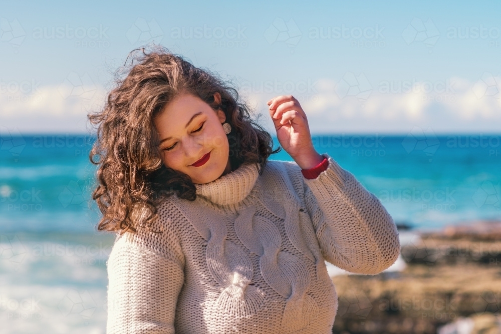 young woman in a jumper by the ocean - Australian Stock Image