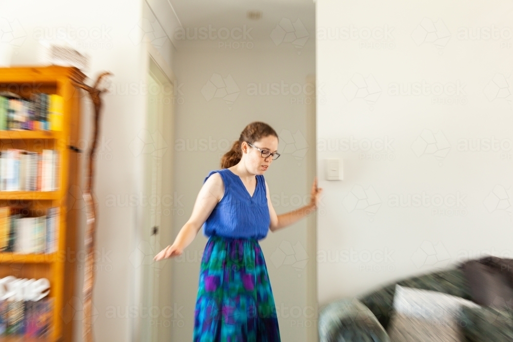 young woman in her twenties leaning on doorframe experiencing vertigo, spinning, dizziness - Australian Stock Image