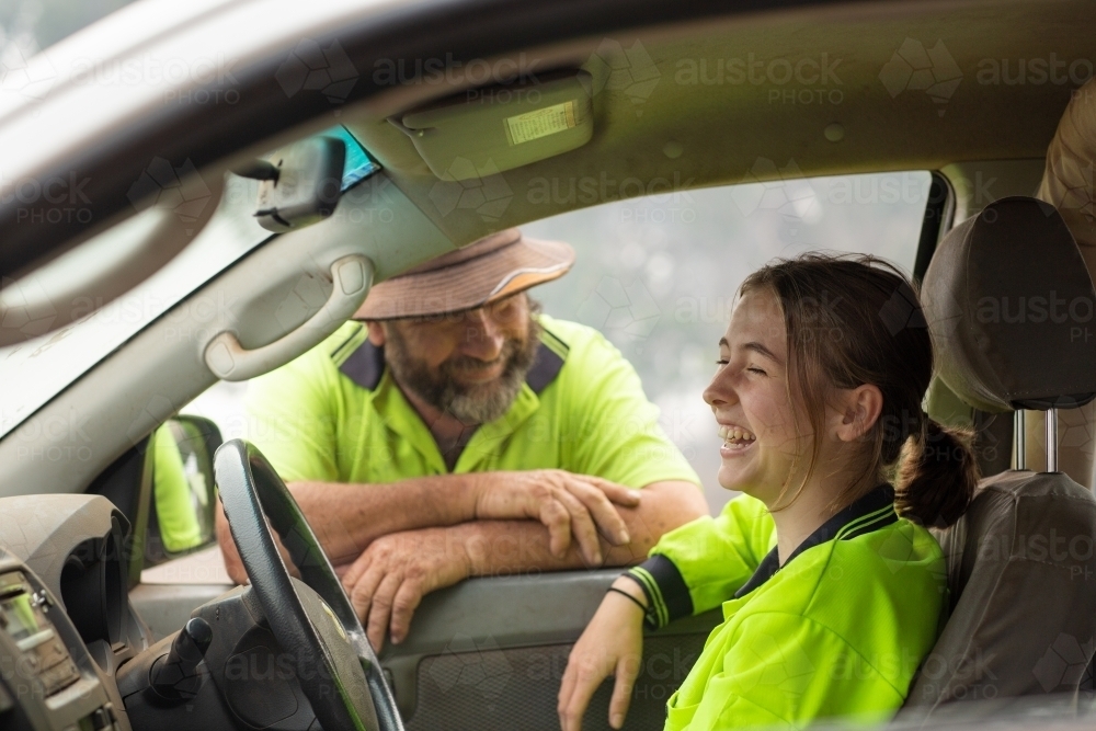Young woman in hi-vis laughing with boss - Australian Stock Image