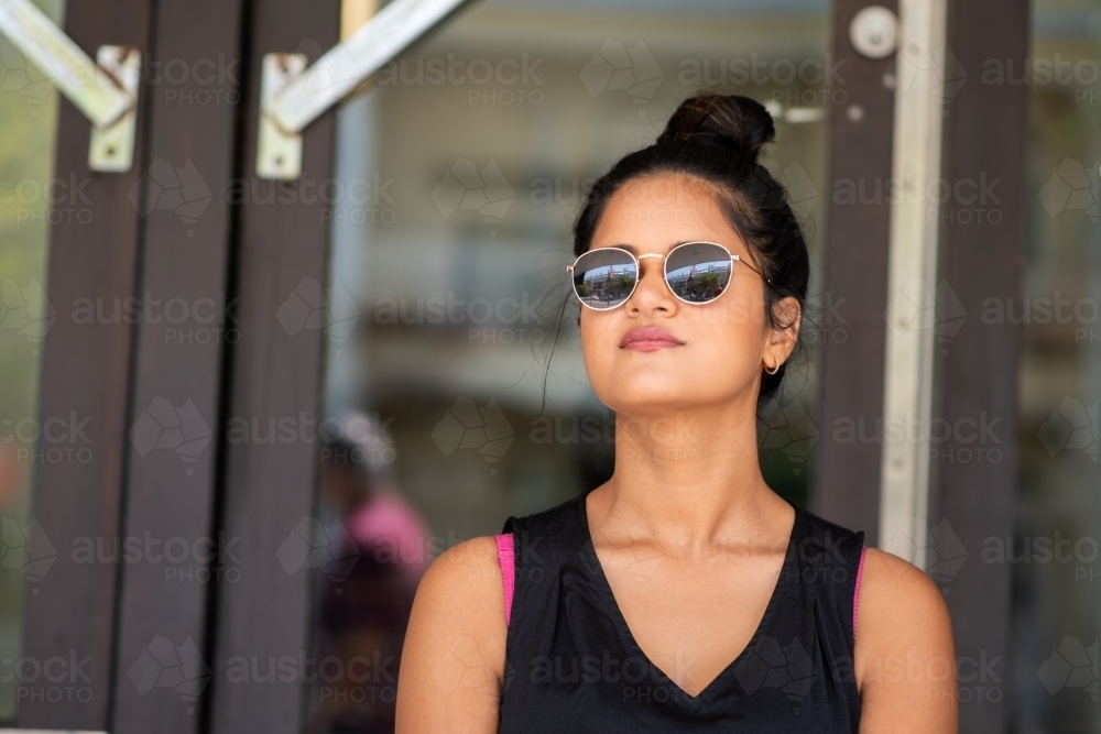 young woman in sunglass on the stairs outside a building - Australian Stock Image