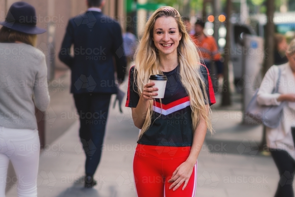 young woman in the city with coffee, wearing sports wear - Australian Stock Image