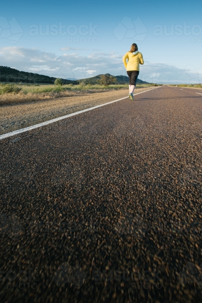 Young woman jogging on a country road - Australian Stock Image