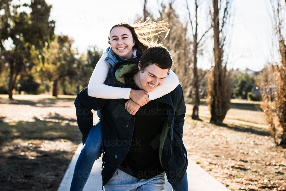 Young woman laughing having piggy back ride from boyfriend - Australian Stock Image