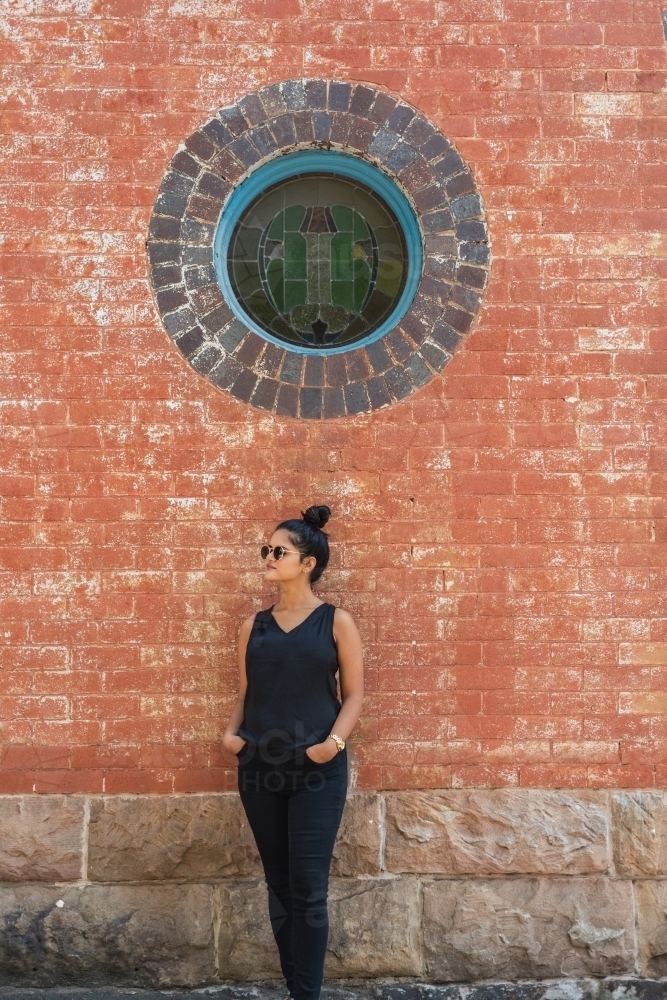 young woman leaning against a brick wall - Australian Stock Image