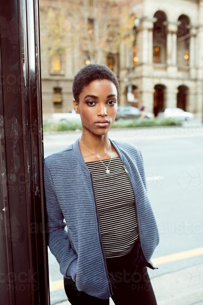 Young woman leaning on a pole on the street - Australian Stock Image
