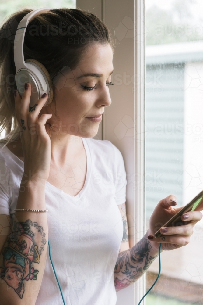 Young woman listening to music with headphones and her smart phone - Australian Stock Image