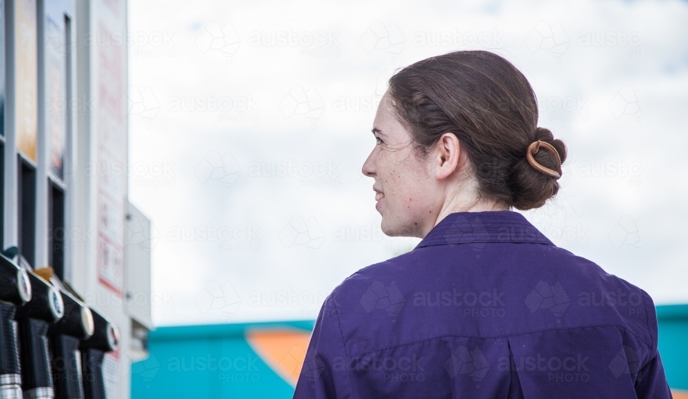 Young woman looking at price on petrol pump at the service station - Australian Stock Image