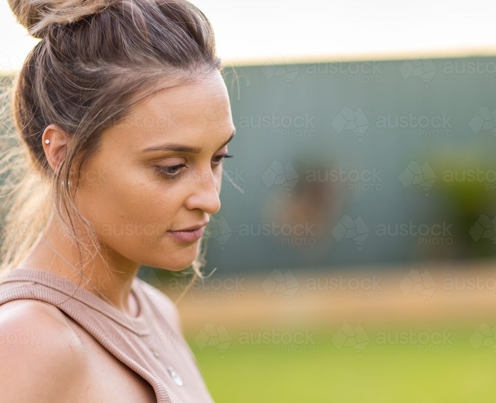 young woman looking down with hair in messy bun - Australian Stock Image