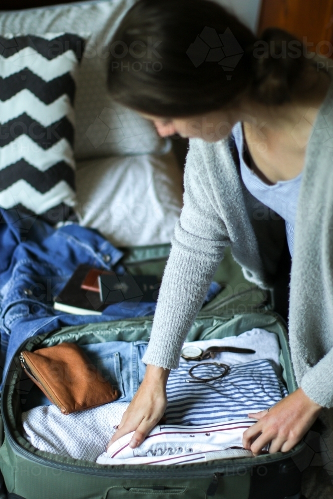 Young woman packing her bag ready to travel - Australian Stock Image
