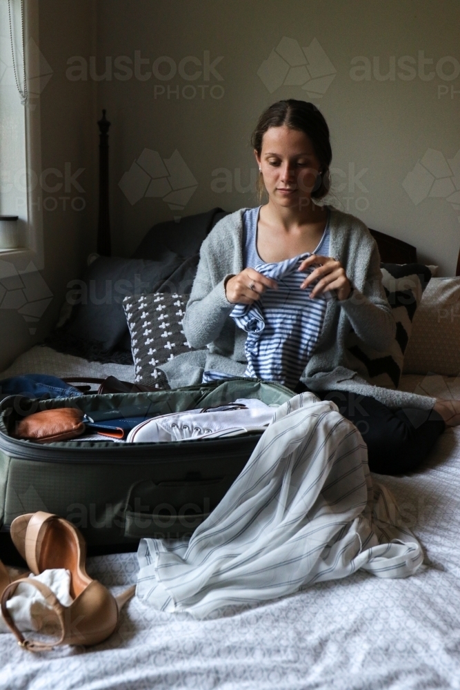 Young woman packing her bag ready to travel - Australian Stock Image