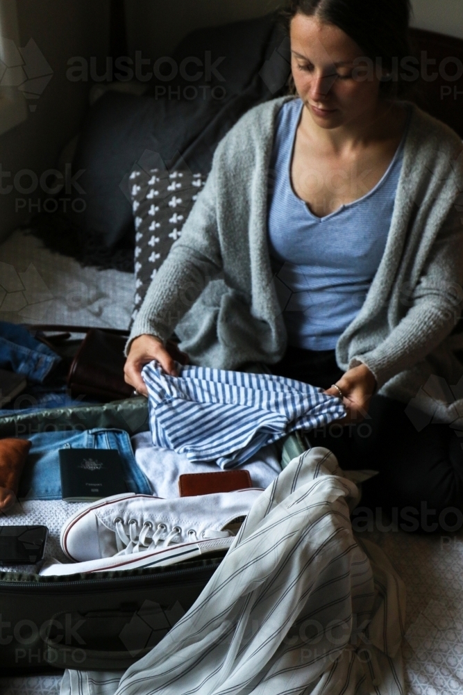 Young woman packing her bag ready to travel - Australian Stock Image