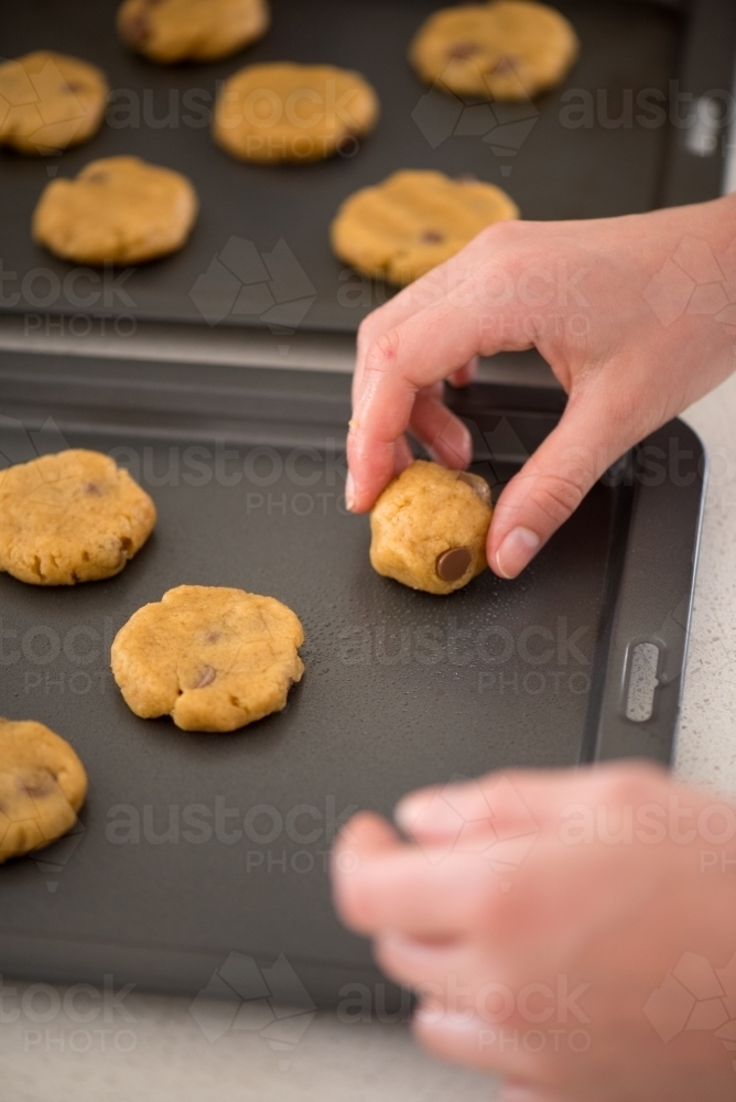 Young woman placing cookie dough onto baking trays - Australian Stock Image