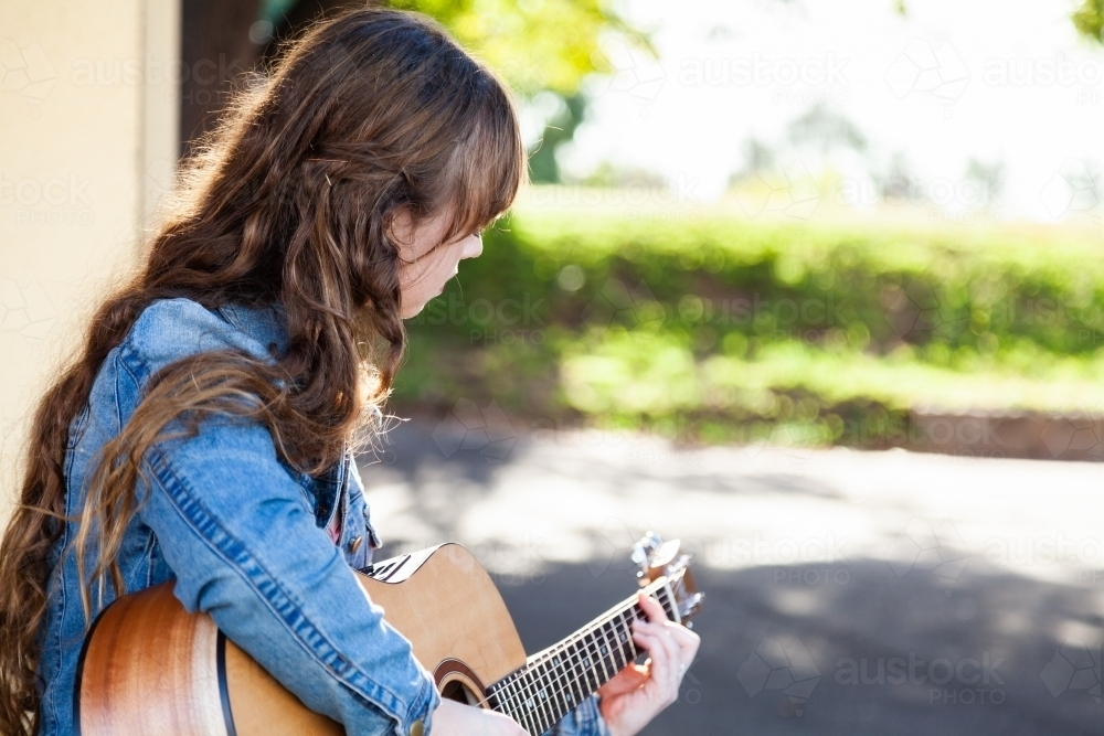 Young woman playing guitar busking with copy space - Australian Stock Image