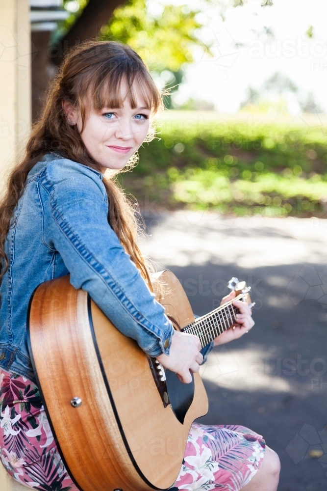 Young woman playing guitar busking with copy space - Australian Stock Image