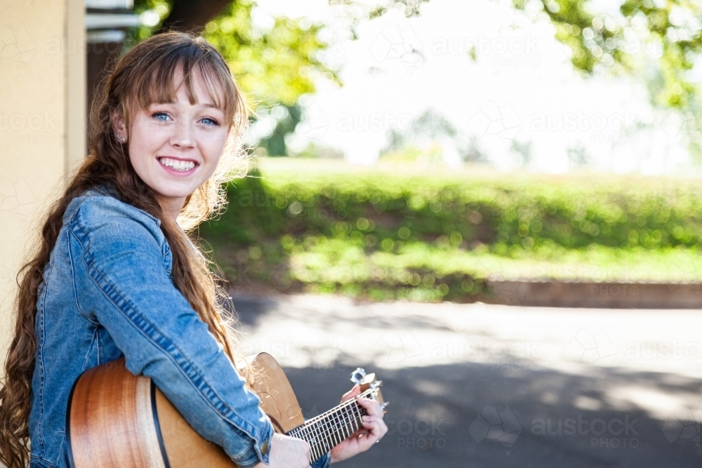 Young woman playing guitar busking with copy space - Australian Stock Image