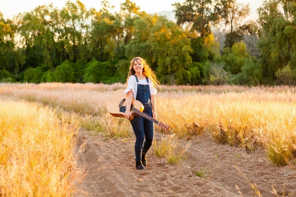 Young woman posing with guitar outside - Australian Stock Image