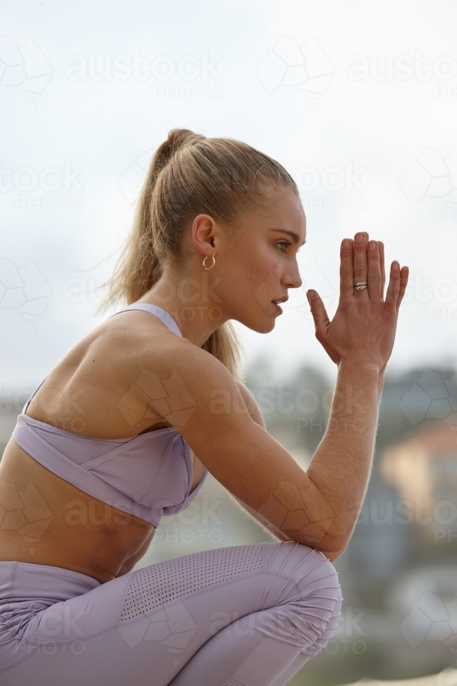 Young woman practising yoga by ocean - Australian Stock Image
