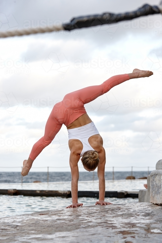 Young woman practising yoga by ocean - Australian Stock Image