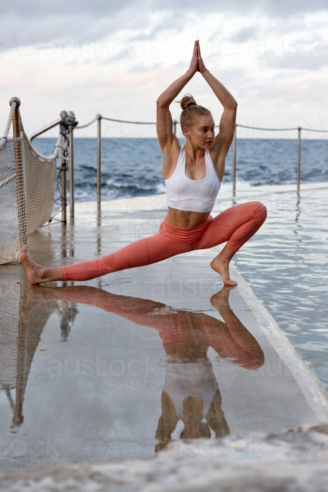 Young woman practising yoga by ocean - Australian Stock Image