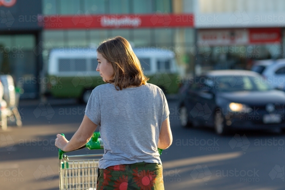 Young woman pushing shopping trolley seen from behind - Australian Stock Image