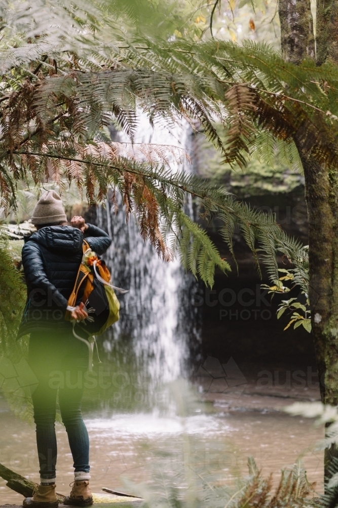 Young woman putting on backpack during bushwalk in nature - Australian Stock Image