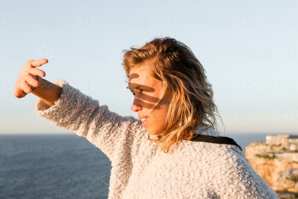 Young woman shielding morning sunlight from her eyes - Australian Stock Image