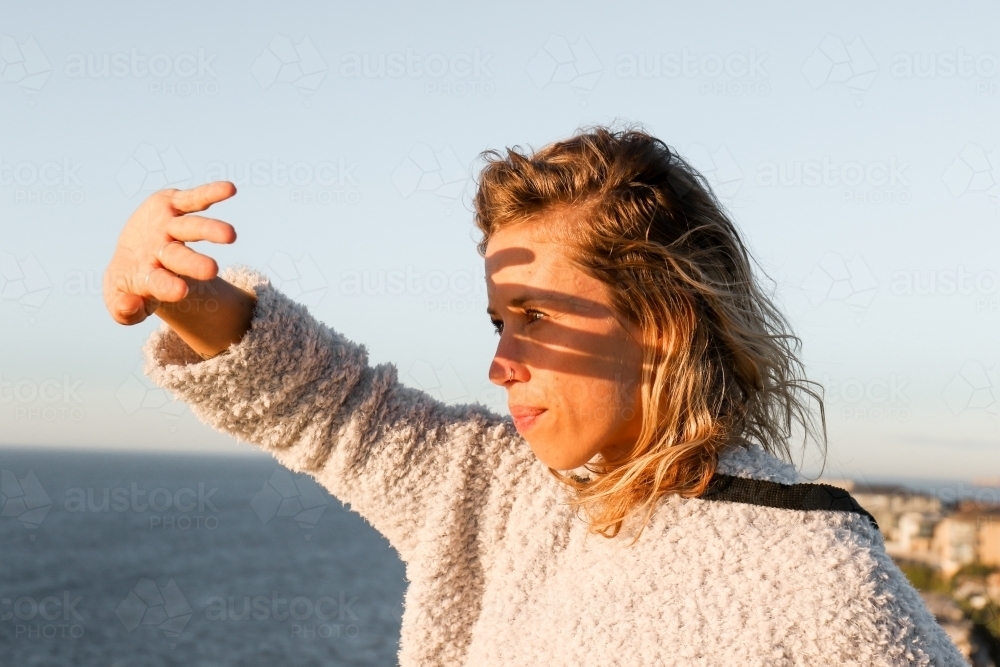 Young woman shielding morning sunlight from her eyes - Australian Stock Image
